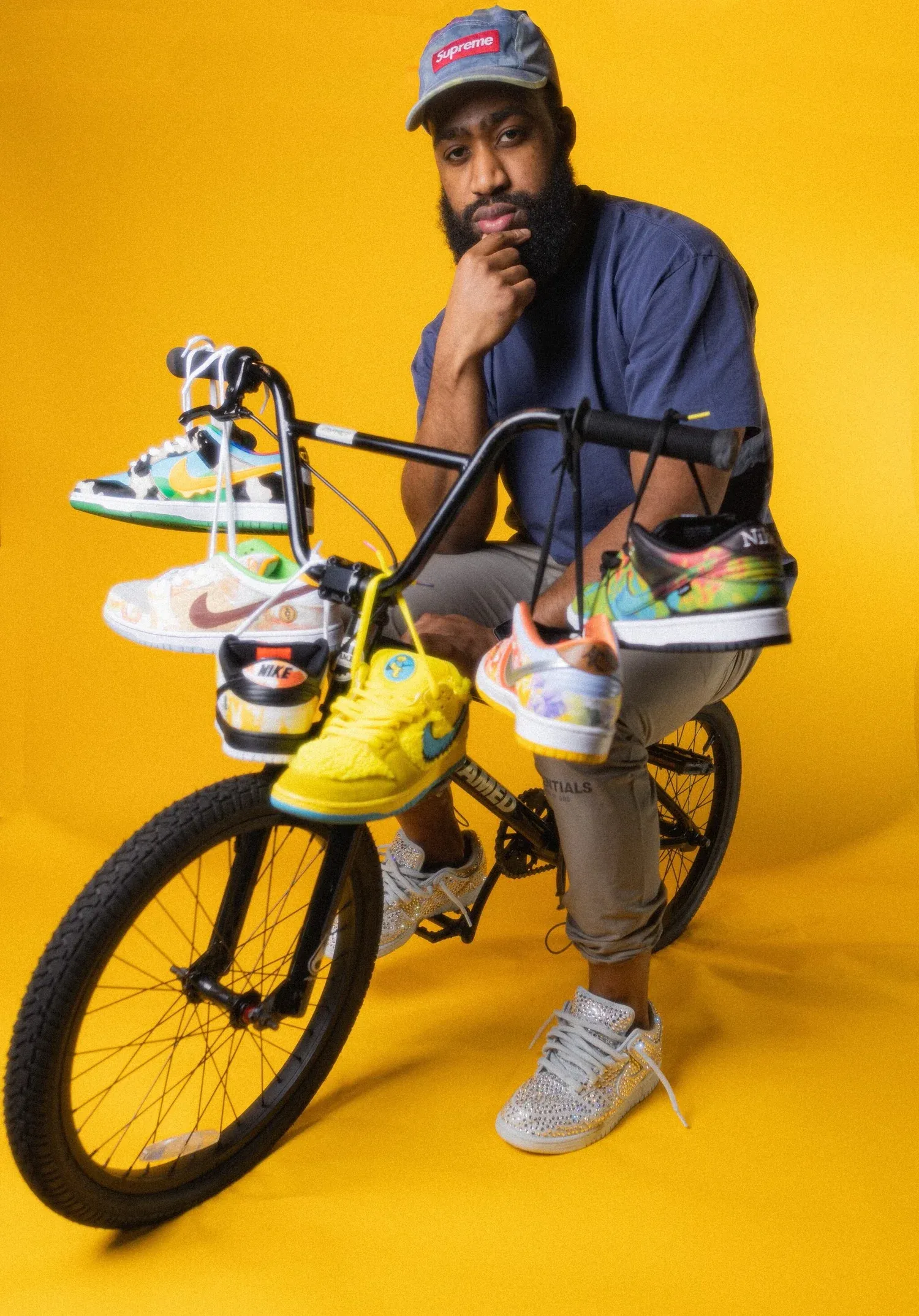 Kelechi on a bike holding sneakers against a yellow backdrop