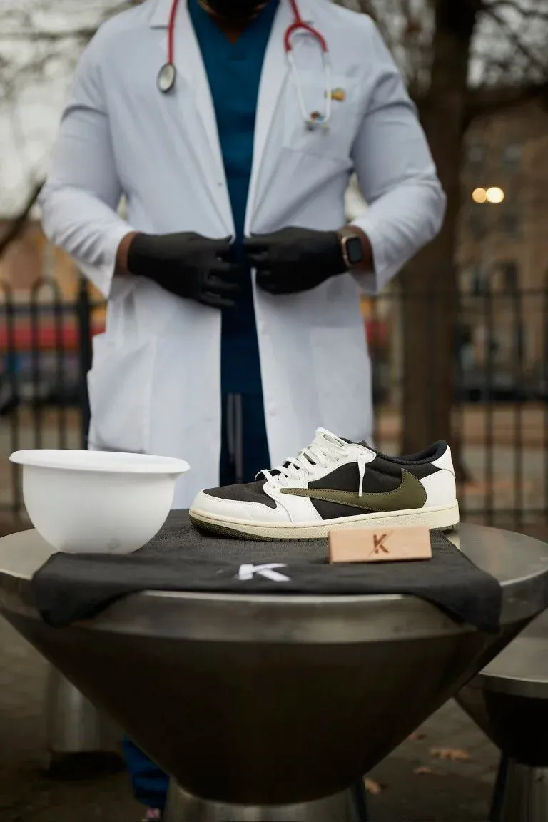 Kelechi in a white coat beside a pair of sneakers on a K3 stand